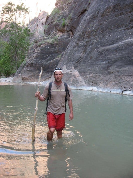 man wading through river in the narrows with hiking pole