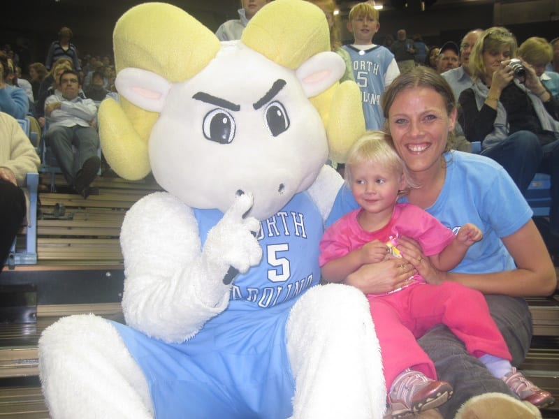 a woman and child sitting next to a basketball mascot 