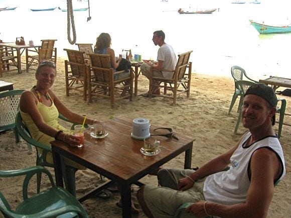 people sitting at tables on the beach