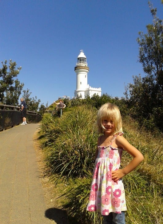 A little girl standing in front of a lighthouse