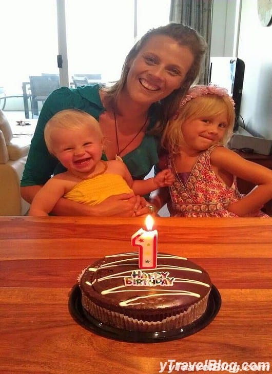 a woman sitting with two kids at a table with a birthday cake