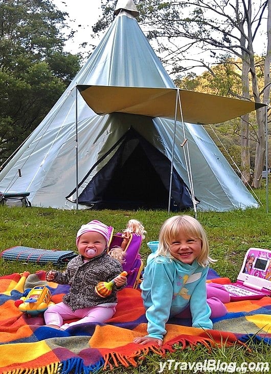 girls sitting in front of a camping tent