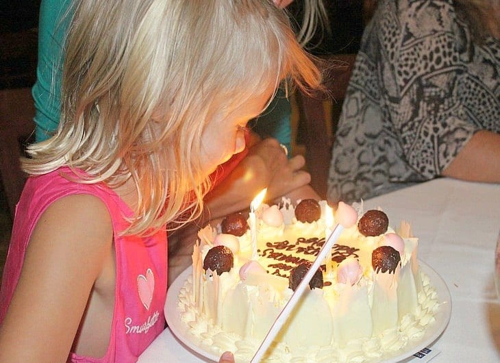 a girl blowing candles out on her birthday cake
