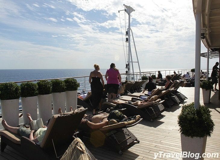 people lying on lounge chairs on a cruise ship deck