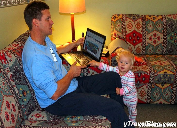 a man working on his computer while a child holds his leg