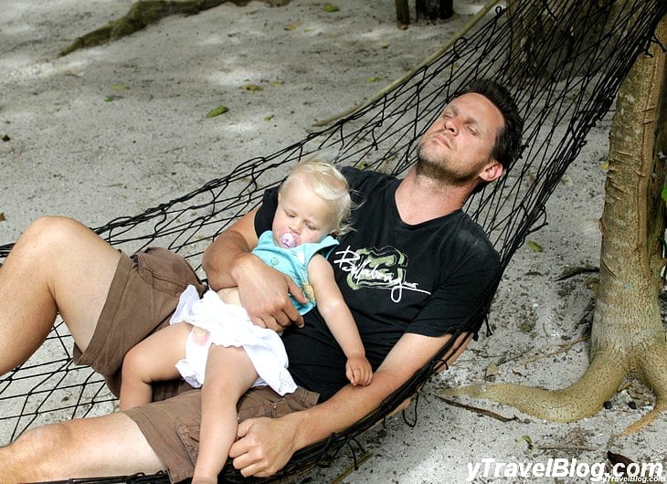 a man and baby sleeping on a hammock 