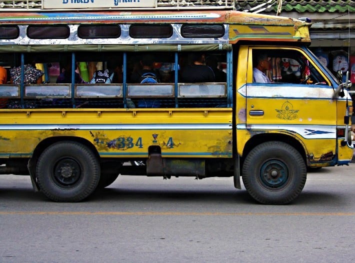 a yellow songthaew fillled with people