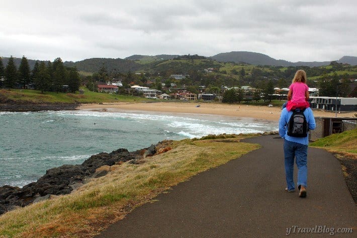 man with girl on shulders walking beach path