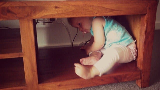 girl hikding under tv cabinet