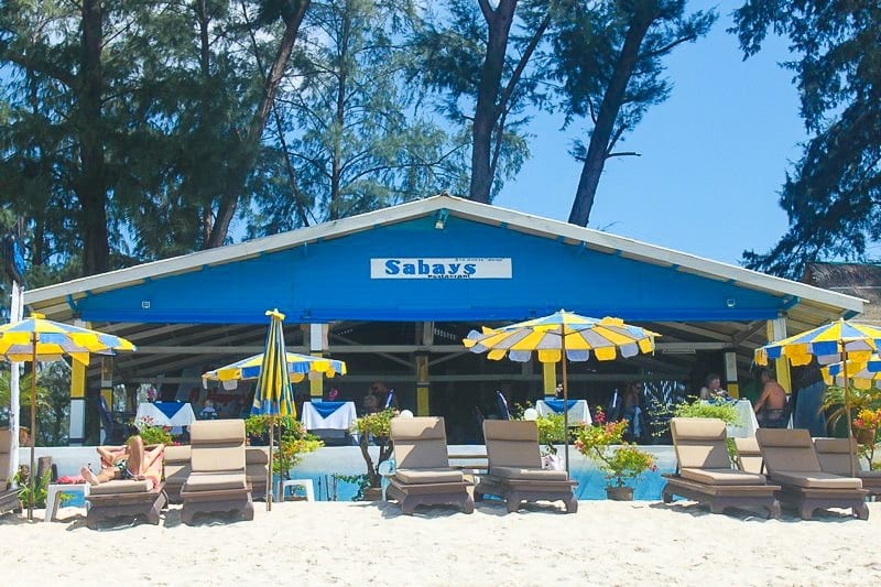 beach chairs and umbrellas on the sand in front of a building