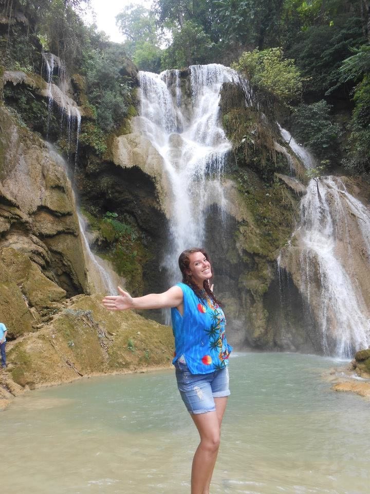 woman standing with arms outstretched near waterfall