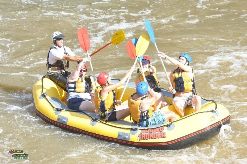 rafting group high fiving paddles in boat