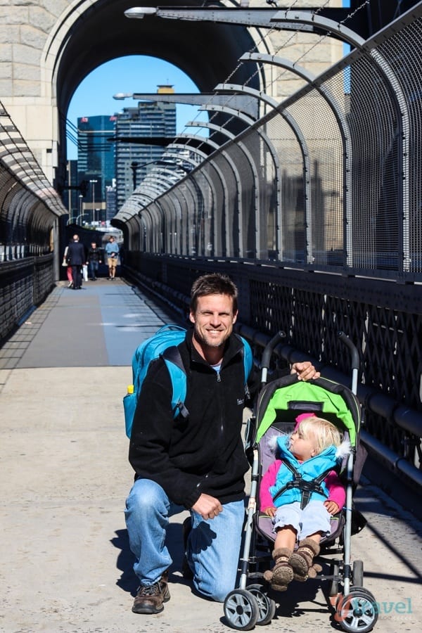 man and child in stroller walking across the sydney harbor bridge