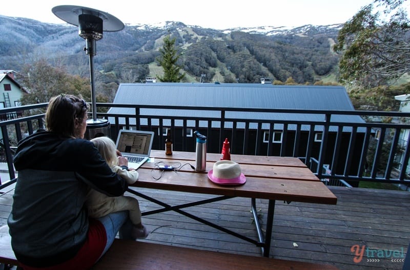 woman working on laptop with child on lap and mountain views