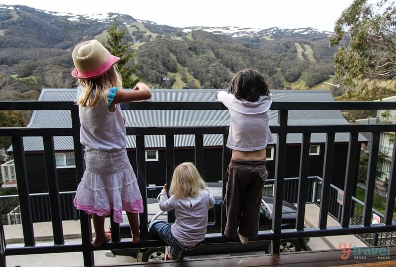 kids on balcony looking at view of snowy mountains