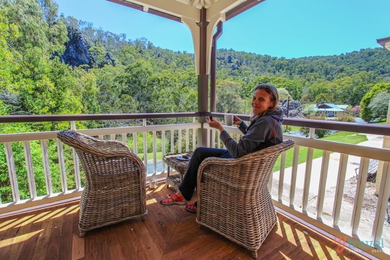 woman sittin gon verandah with cup of tea looking at view. 