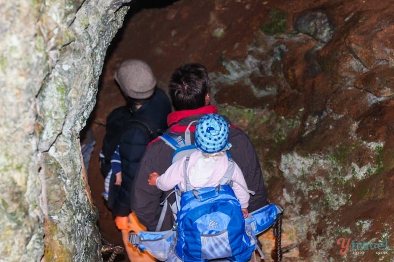 baby on mans back walking into caveYarrangobilly Caves, Snowy Mountains, Australia