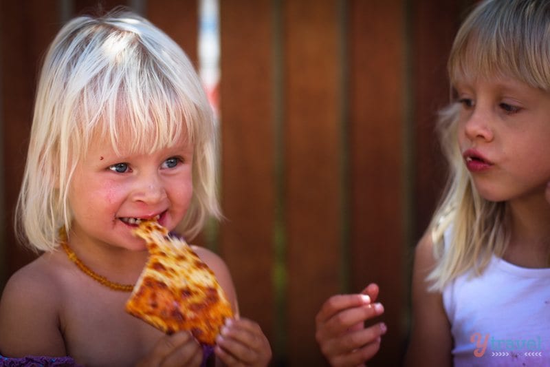 A little girl eating a slice of pizza