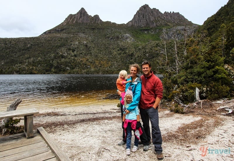 a family standing in front of a lake with mountains behind them