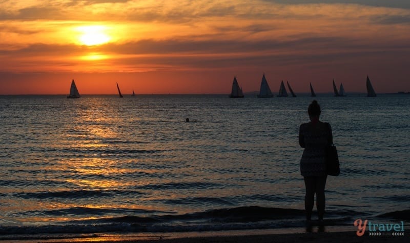 silhouette of boats and woman watching Sunset at St Kilda Beach, Melbourne, Australia