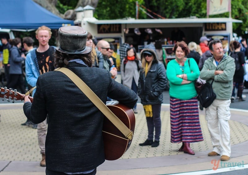 crowd of people watching a man play guitar on the street
