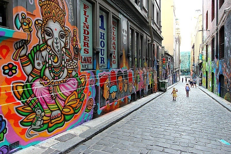 A group of people walking down a sidewalk covered in graffiti