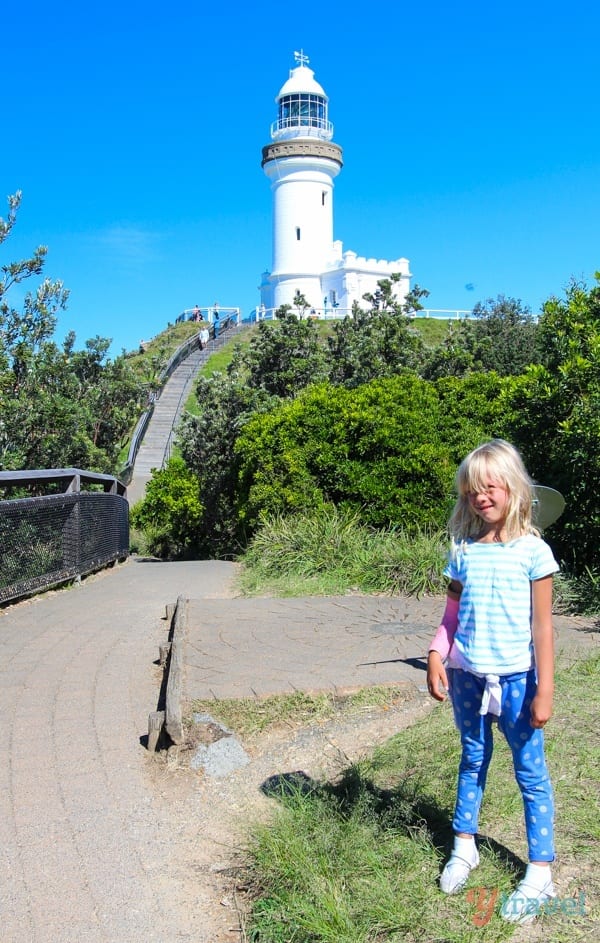 girl standing in front of lighthouse on hill