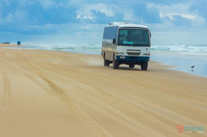 A truck that is driving down the beach
