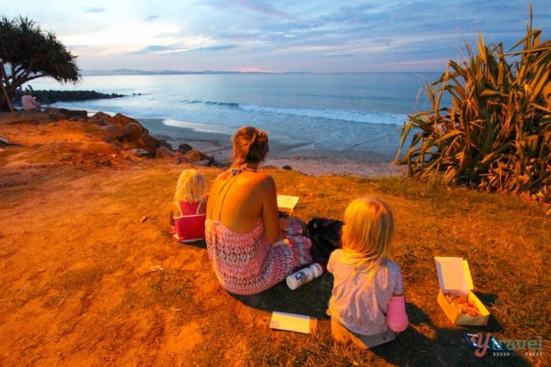 girls sitting on cliff eating and looking at beach