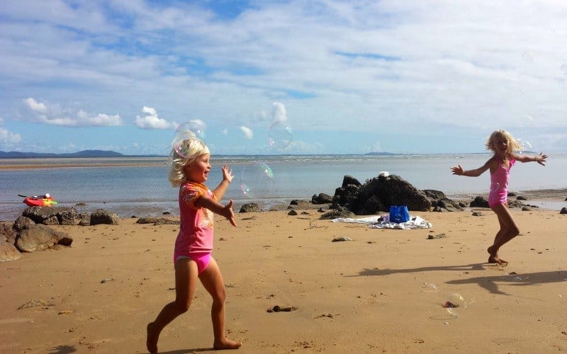 girl chasing bubbles on the beach