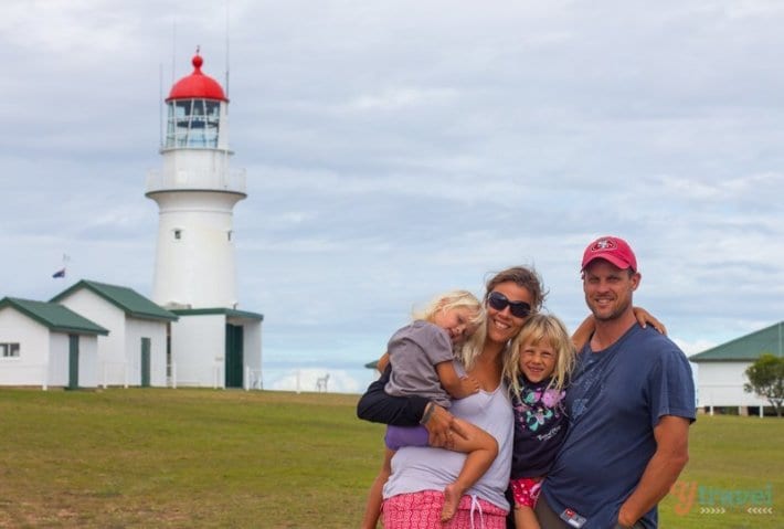 a family standing in front of a light house