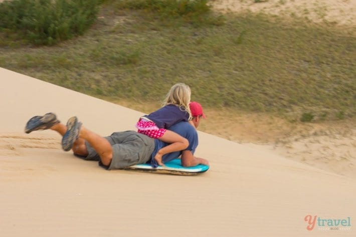people sand boarding down sand dunes
