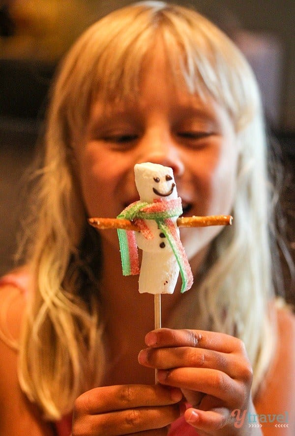 little girl holding up marshmallows on a stick