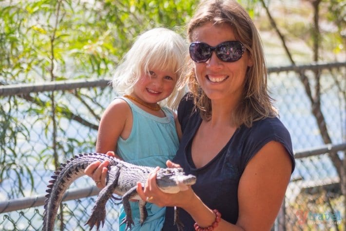 people holding a baby crocodile