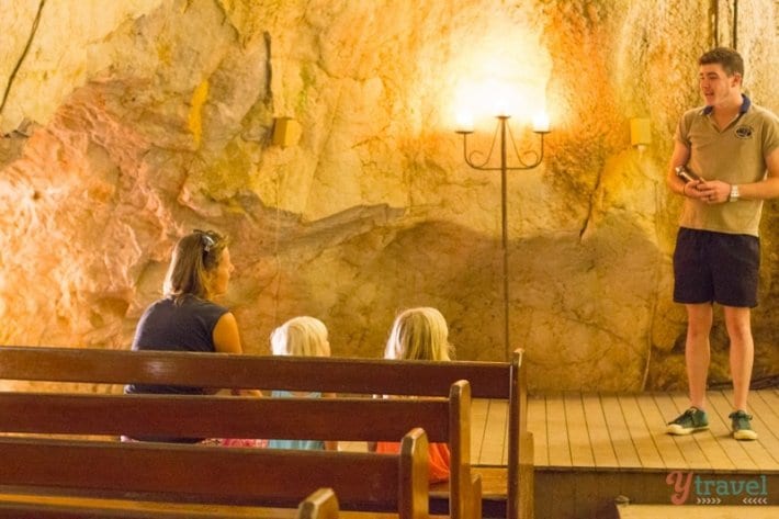 people sitting in a church inside a cave