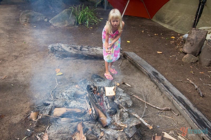 child standing next to fire wood