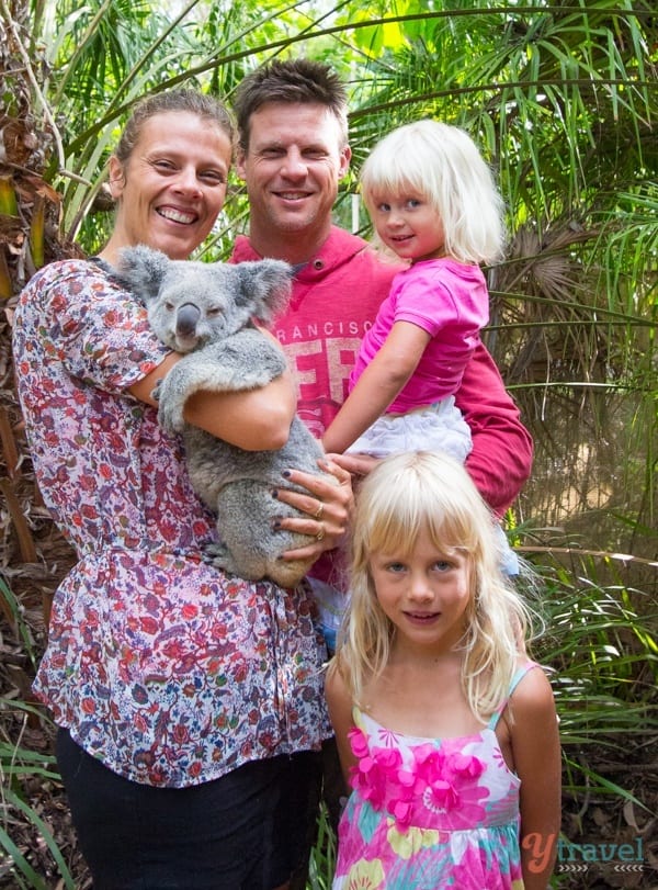 family standing next to a woman holding a koala