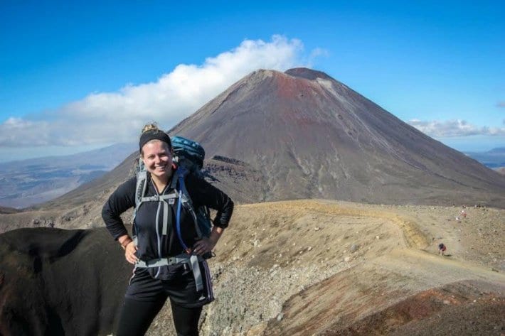 Liz hiking with backpack in front of volcano