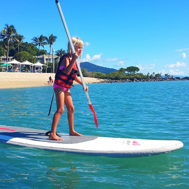 little girl stand up paddle boarding on the beach