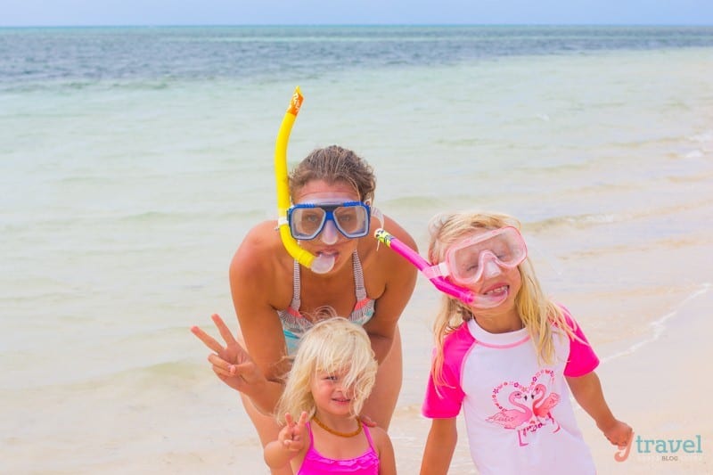 woman and two girls posing with peace signs on a beach