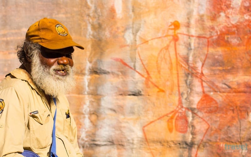 aboriginal elder in front of rock art