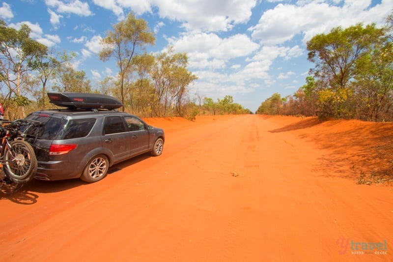A car driving on a red dirt road
