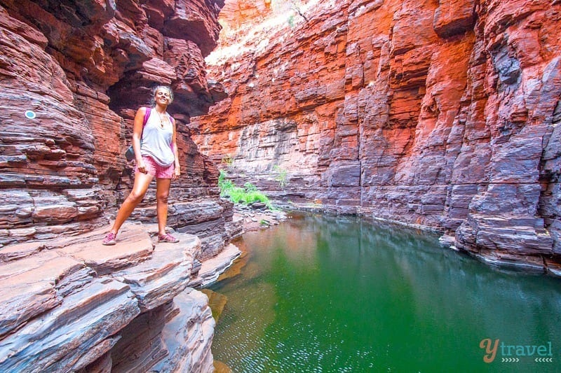 woman standing on a rock next to a river in a canyon
