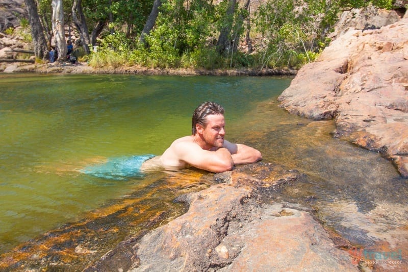 A man sitting on a rock next to water