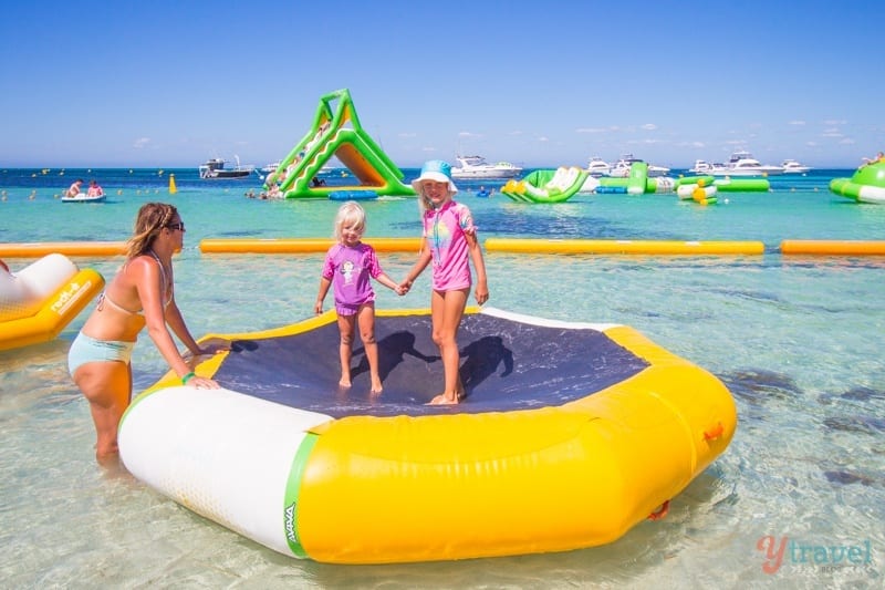 people jumping on an inflatable trampoline in the ocean