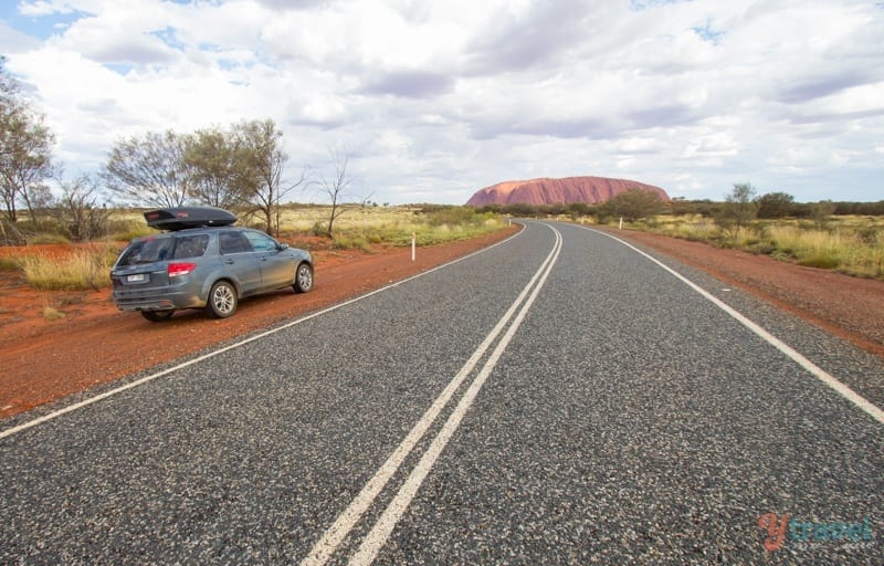 car on road leading to Uluru