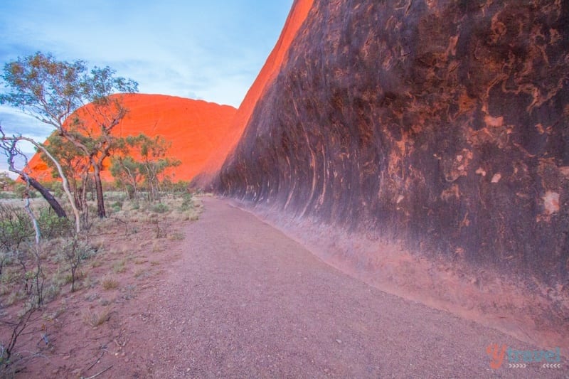 a path alongside a big red rock