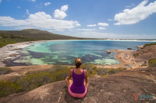 woman meditating on a rock overlooking the beach