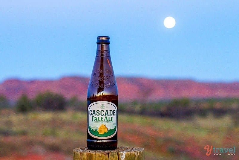 A bottle of cascade pale ale on stump in outback with moon rising