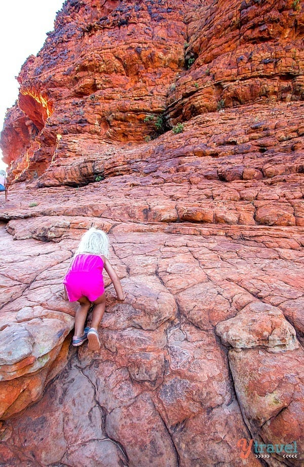 little girl climbing up a rock